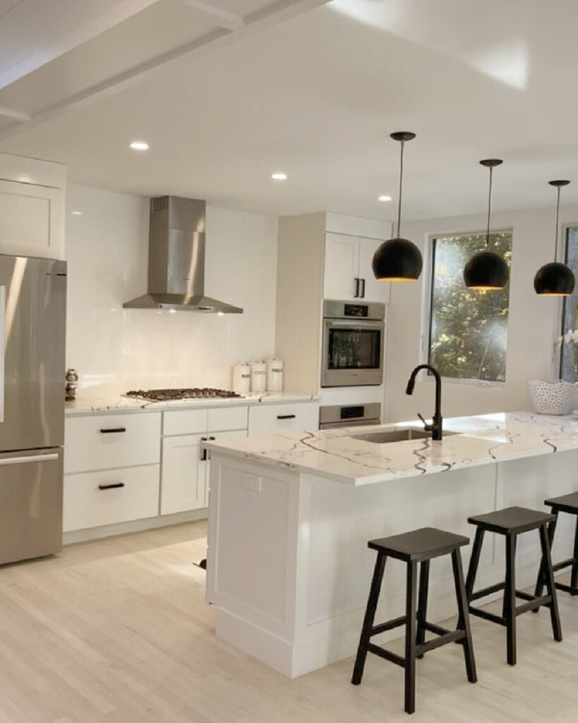 Modern white kitchen remodel with pendant lighting and marble countertop – a key example in why Do It Yourself Home Renovation Guide is best left to professionals