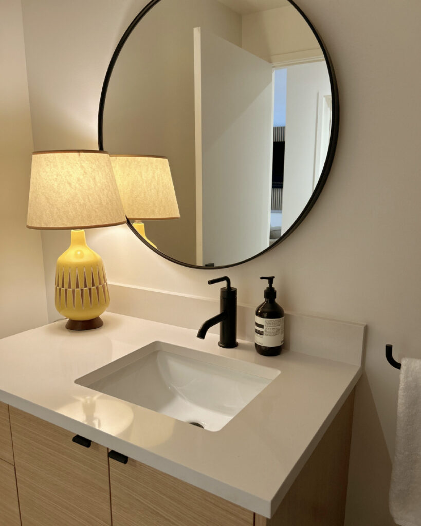 Bathroom vanity update with modern round mirror and matte black fixtures – a small project suitable for beginners following our blog Do It Yourself Home Renovation Guide.